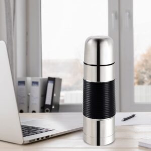 A stainless steel thermos bottle on a desk next to a laptop.
