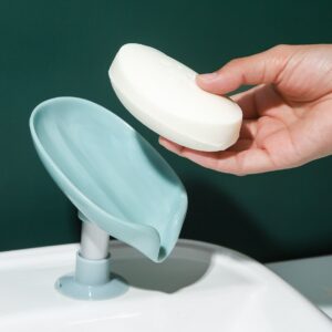 A hand is holding a soap dish on top of a sink.