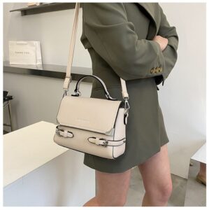 A woman in a green dress holding a beige handbag.