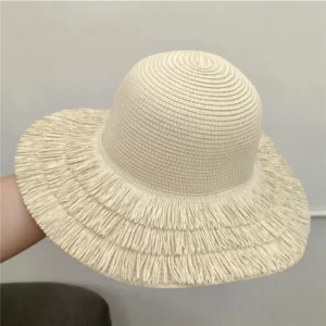 A woman's hand holding a white Straw Hats with fringe Edge.