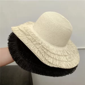 A woman holding a Straw Hat with fringe Edge.