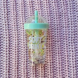 A cup with a straw sitting on top of a knit sweater.