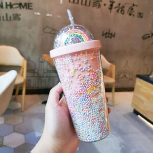 A person holding a 3D Rainbow Glitter Stars Tumbler with sprinkles on it.