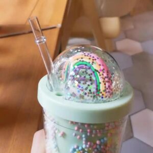 A person holding a 3D Rainbow Glitter Stars Tumbler filled with sprinkles and a straw.