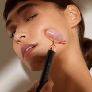 A woman is using the 2 In 1 Electric Vibrating Facial Roller Massager to exfoliate her face.
