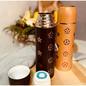 A thermos bottle with stars on it and a cup on a cutting board.