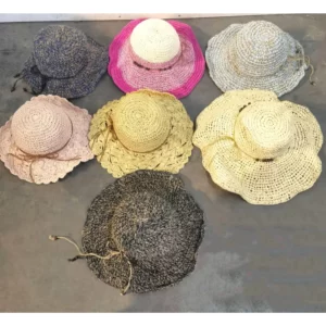 A collection of women's wide brim hats scattered on a concrete floor.