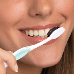A woman is brushing her teeth with Miracle Teeth Whitener Powder.