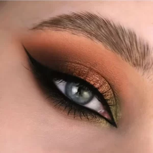 A close up of a woman's eye with brown and orange makeup.