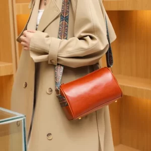 A woman in a trench coat holding The Dawnegy Fashion Crossbody Bag.