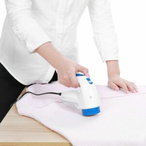 A woman using an electric iron on a white towel.
