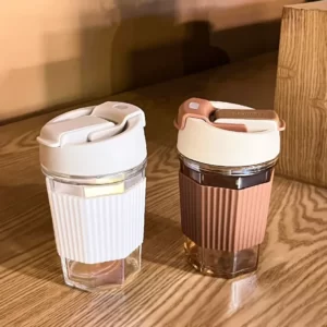 Two Anti Scale Silicone Cover Coffee Cups With Straw on top of a wooden table.