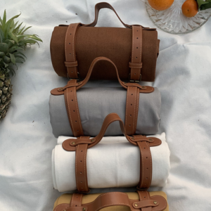 Three brown and tan Solid color picnic out door blankets on a white bed.